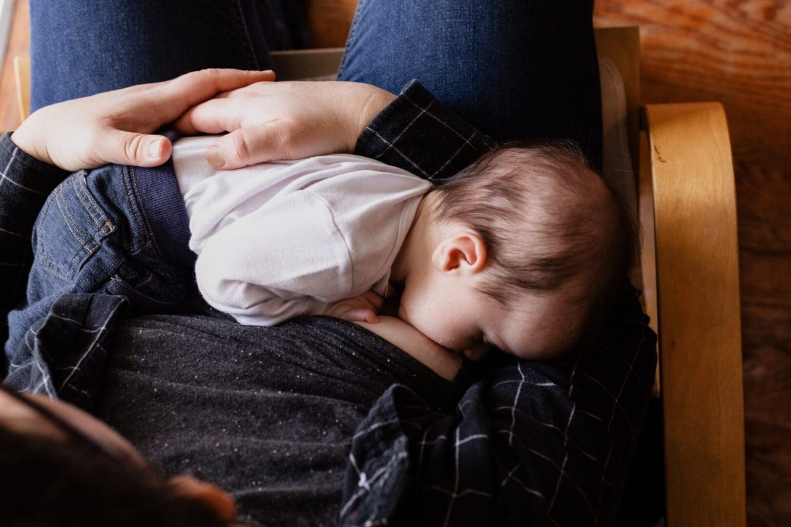 A Baby In White Lying On A Person